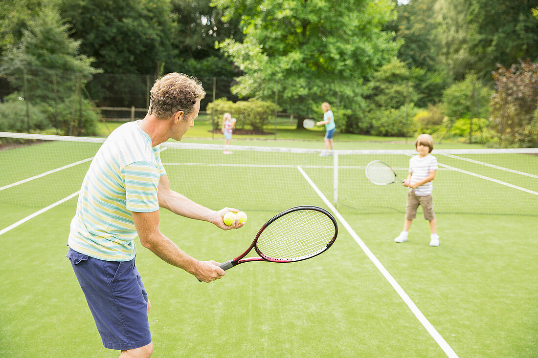 Family playing tennis on grass court