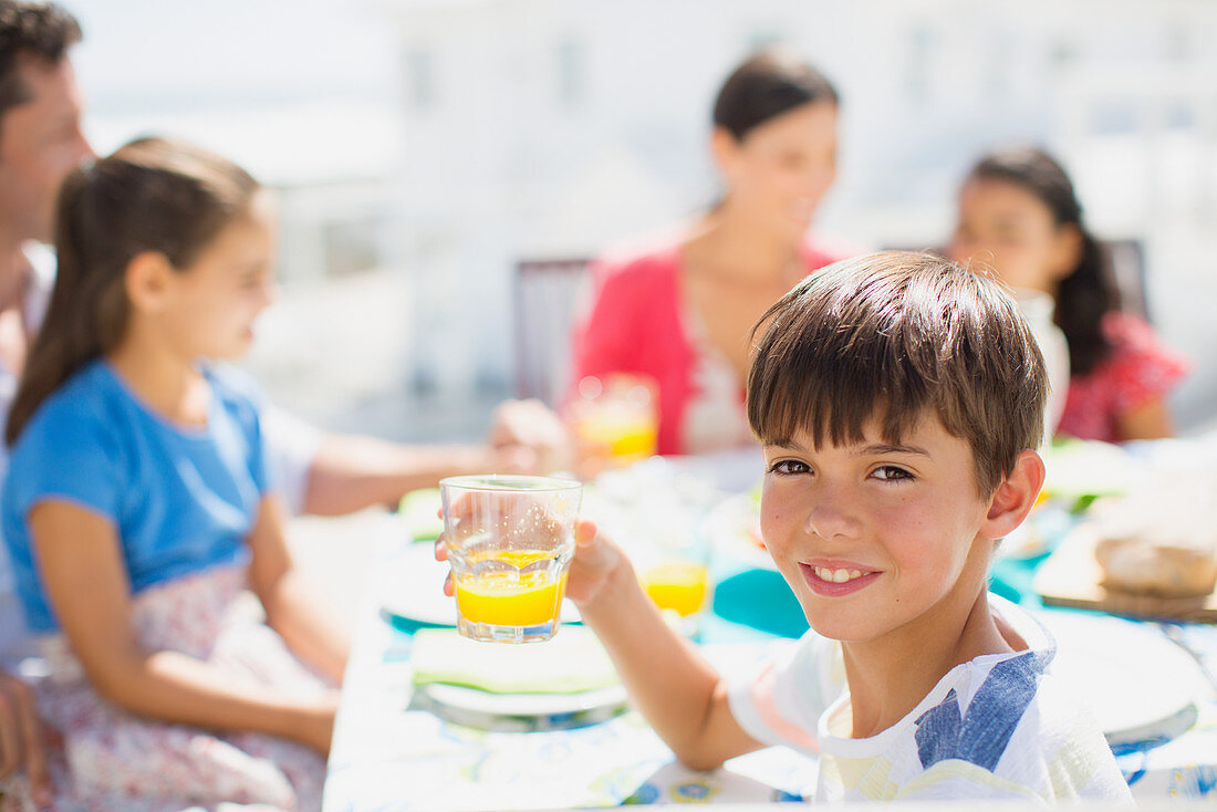 Boy drinking juice at table on patio