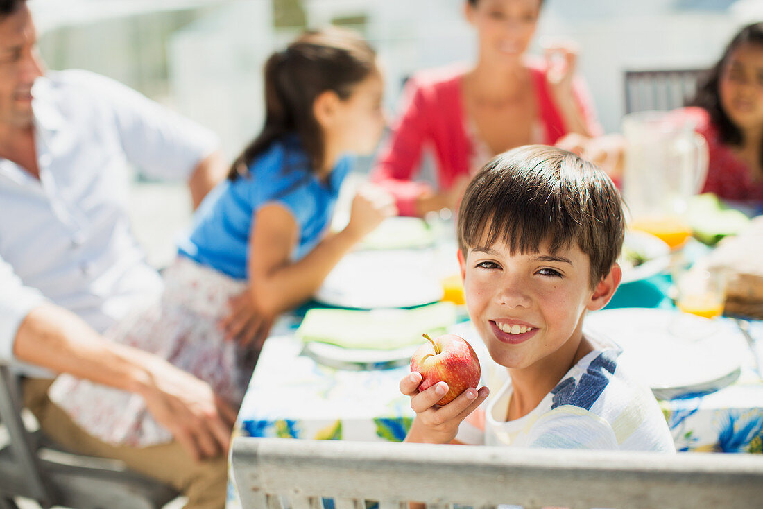 Boy eating fruit with family