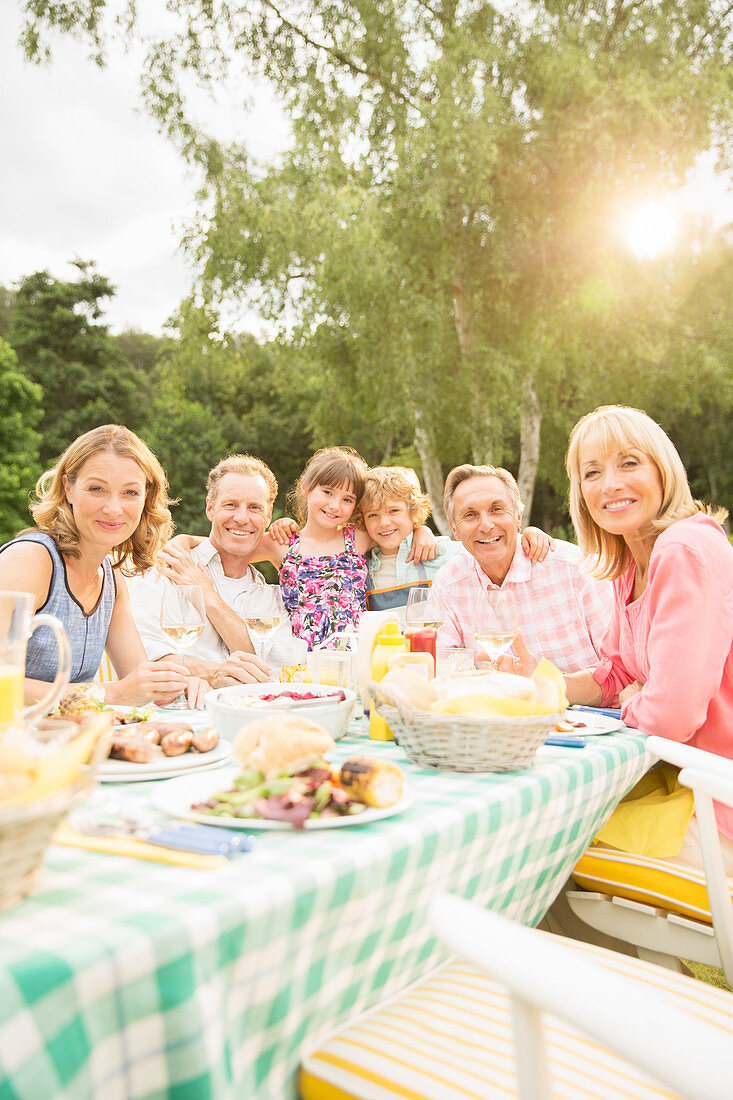 Family eating lunch at table in backyard