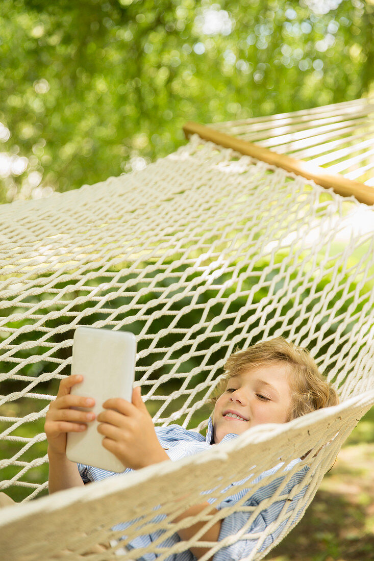 Boy using digital tablet in hammock