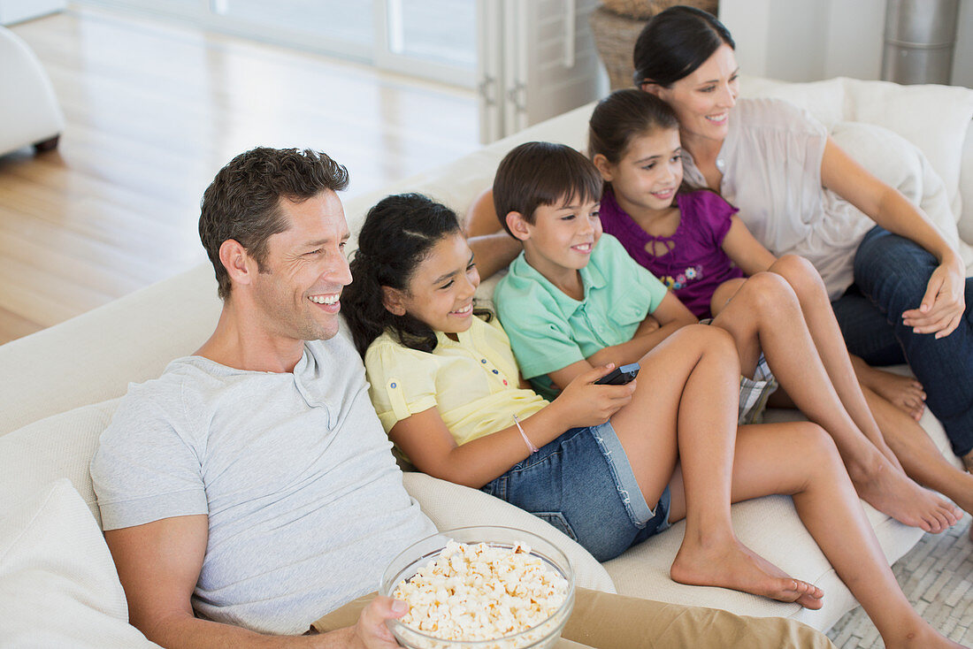 Family watching TV on sofa in living room