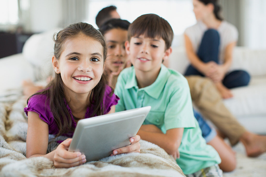Children using digital tablet on sofa