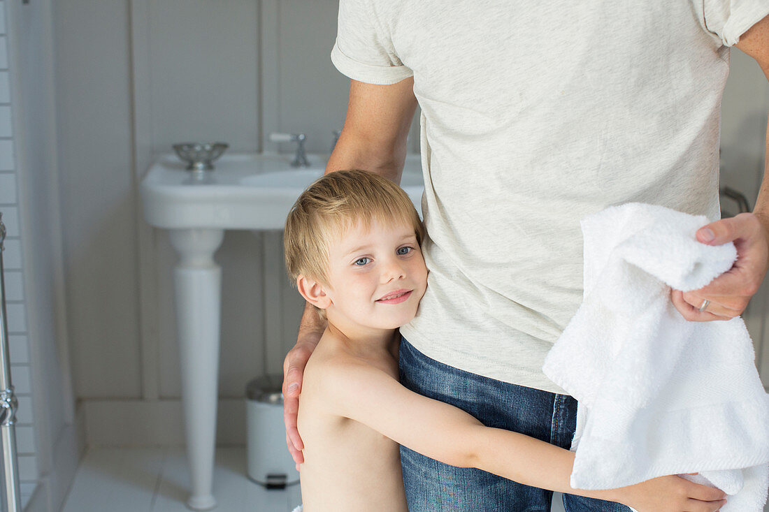 Boy hugging father in bathroom