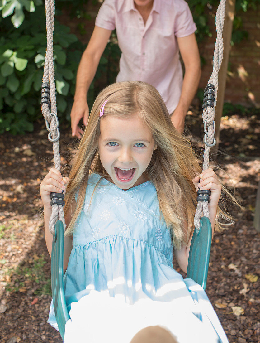 Father pushing daughter in swing