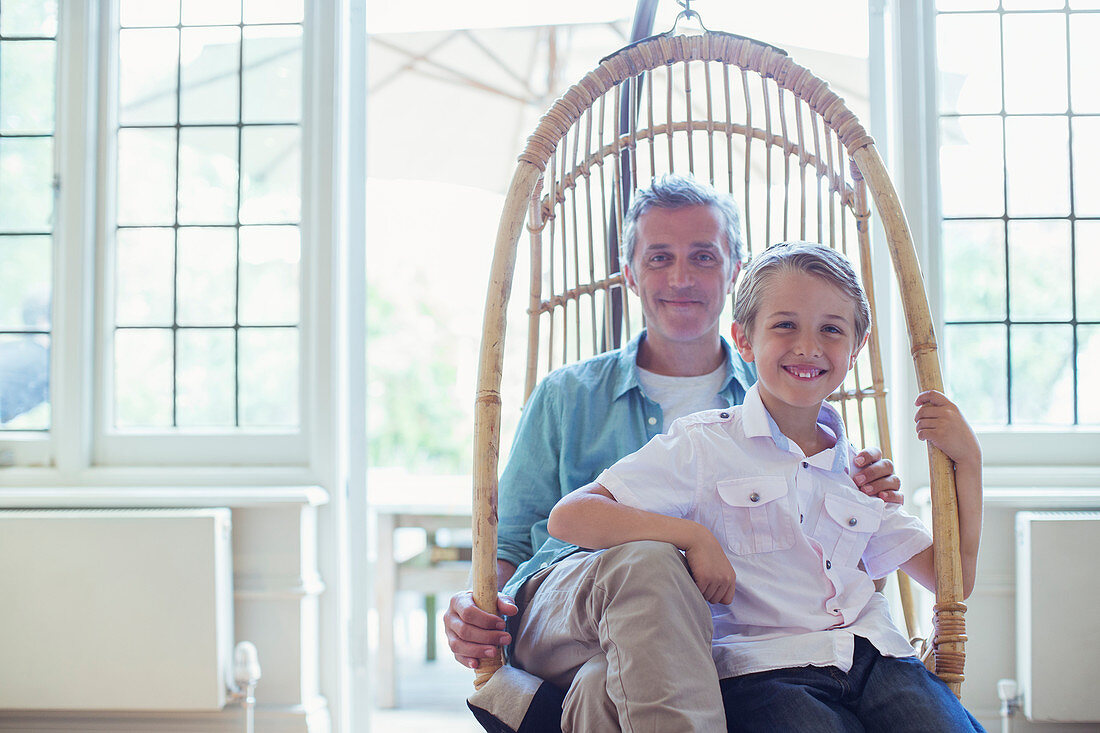 Father and son sitting in wicker chair