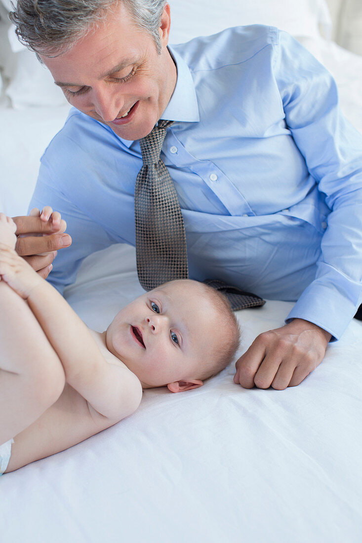 Father playing with baby on bed