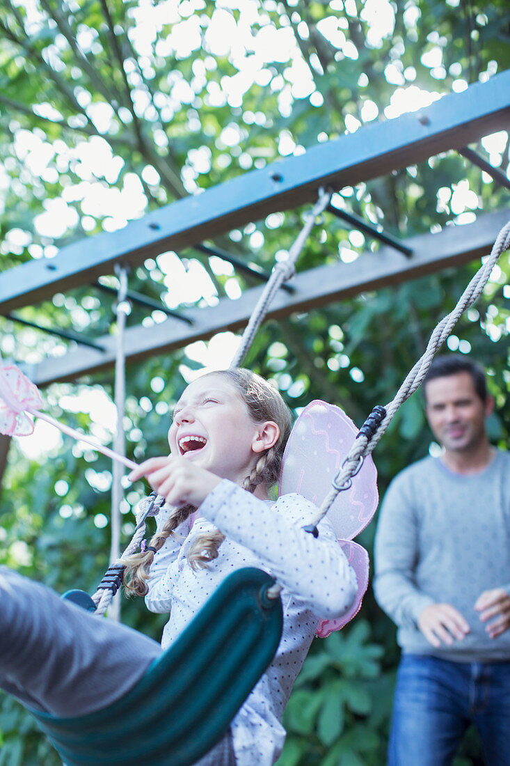 Father pushing daughter on swing outdoors