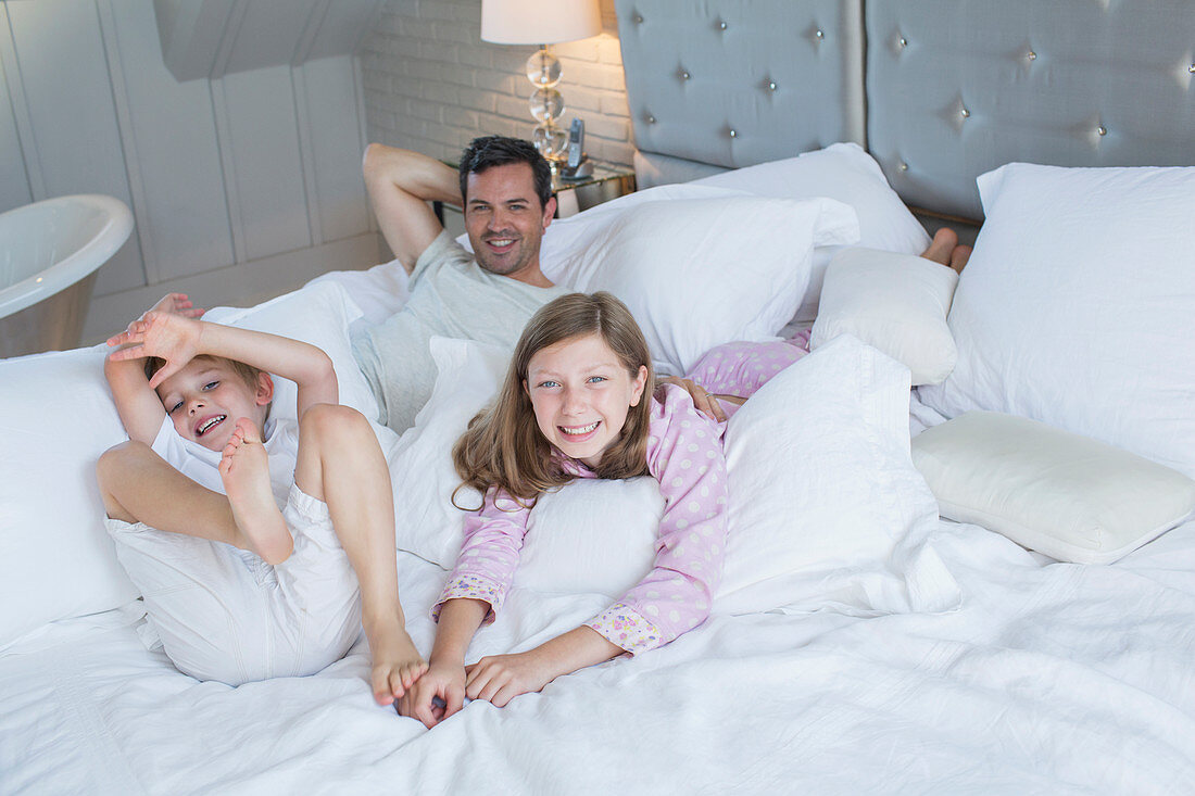 Father and children relaxing on bed