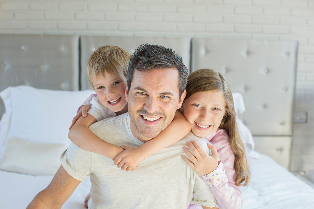 Father and children hugging in bedroom