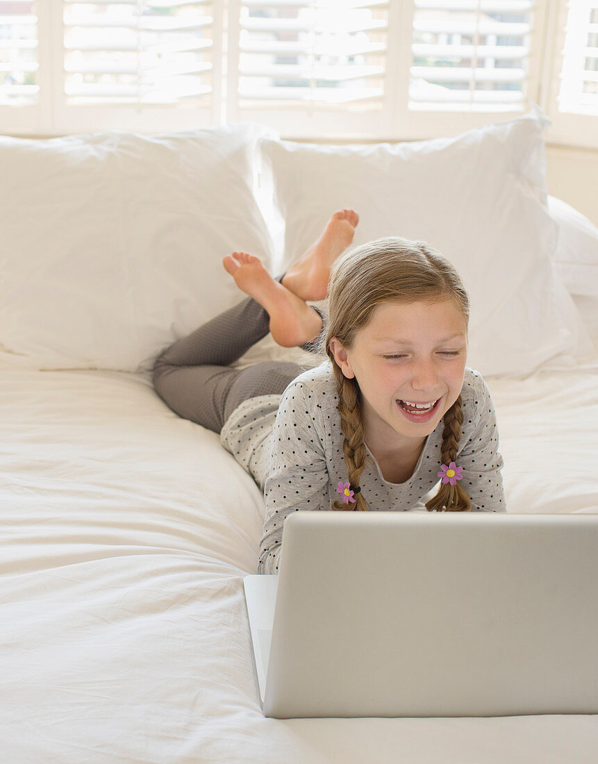 Girl using laptop on bed