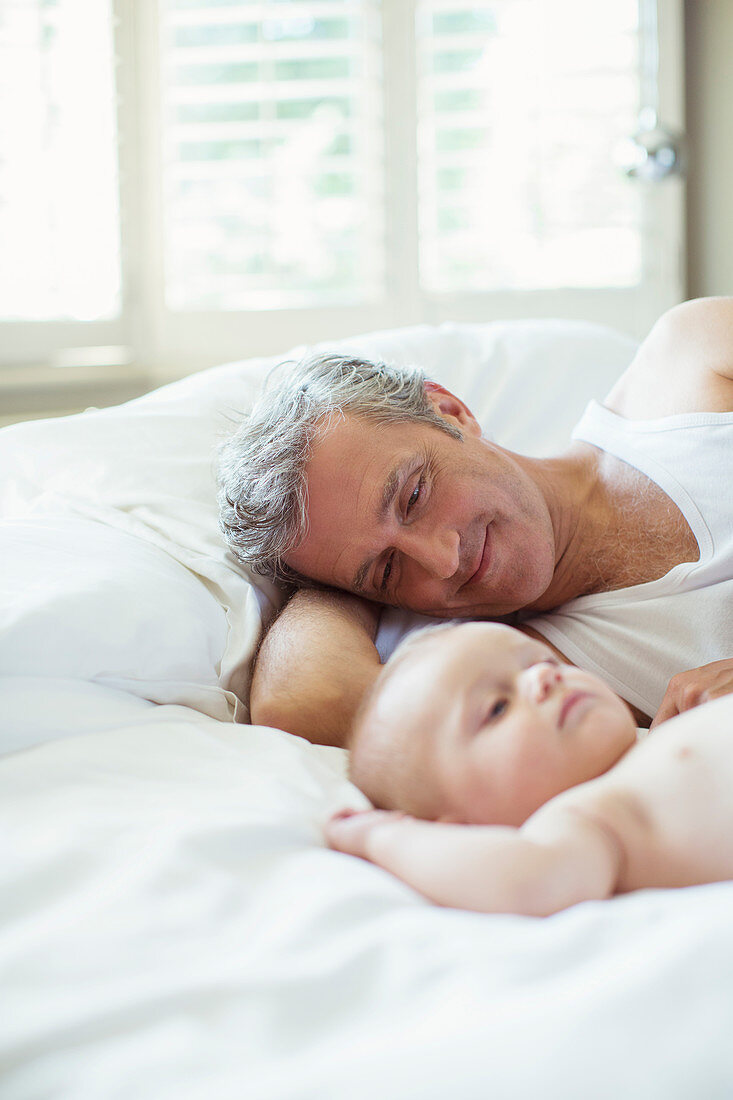 Father and baby laying on bed