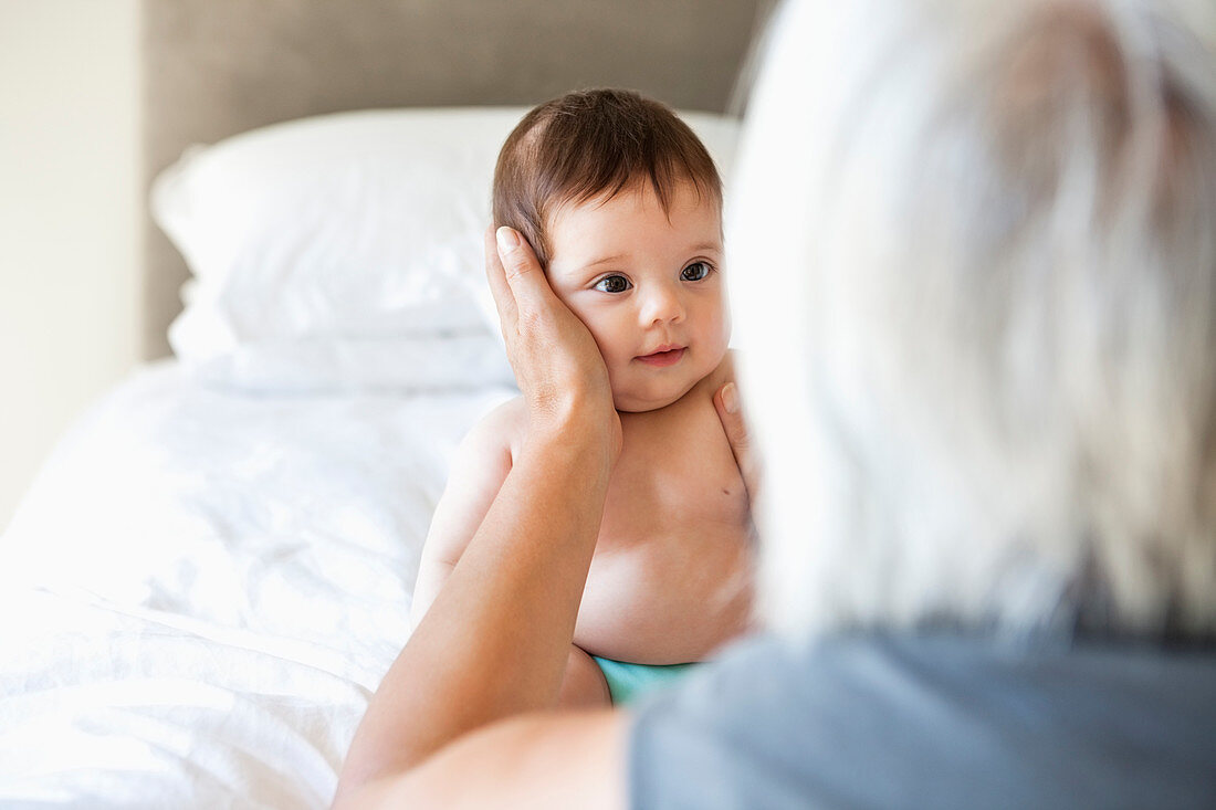 Woman holding granddaughter on bed