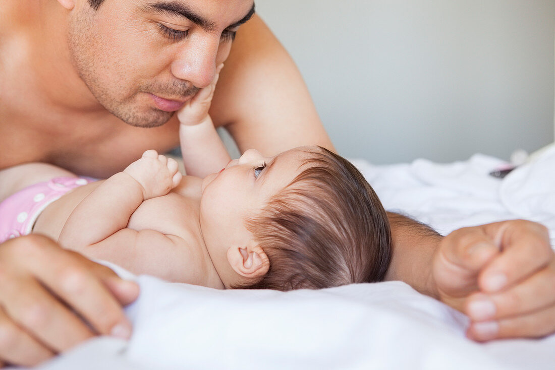 Father admiring baby girl on bed