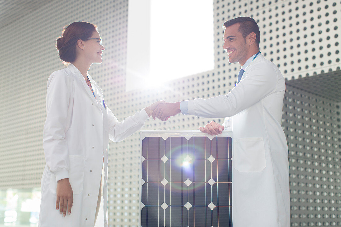 Scientists handshaking at solar panel