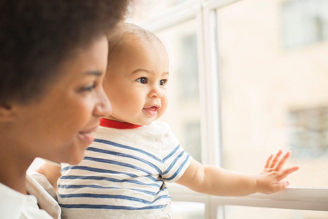 Mother and baby boy looking out window