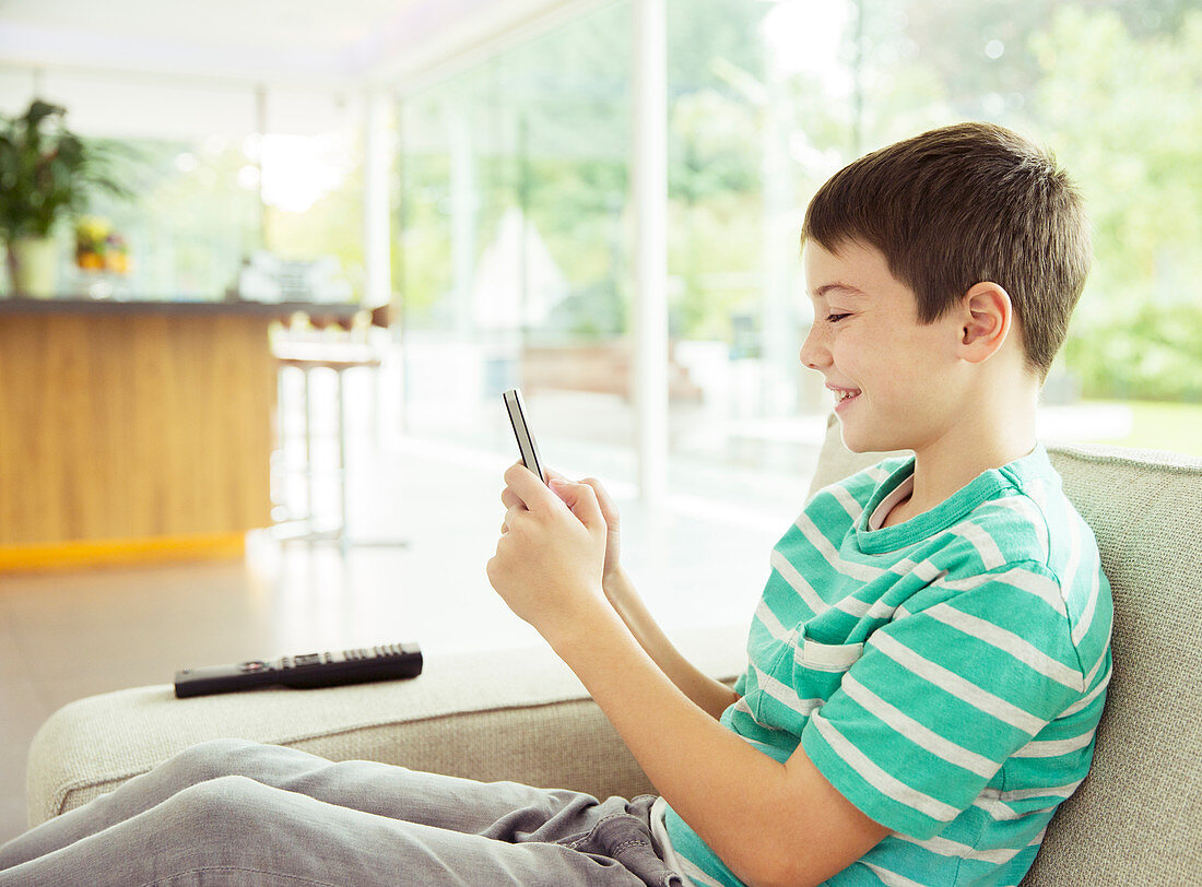 Boy using cell phone on sofa