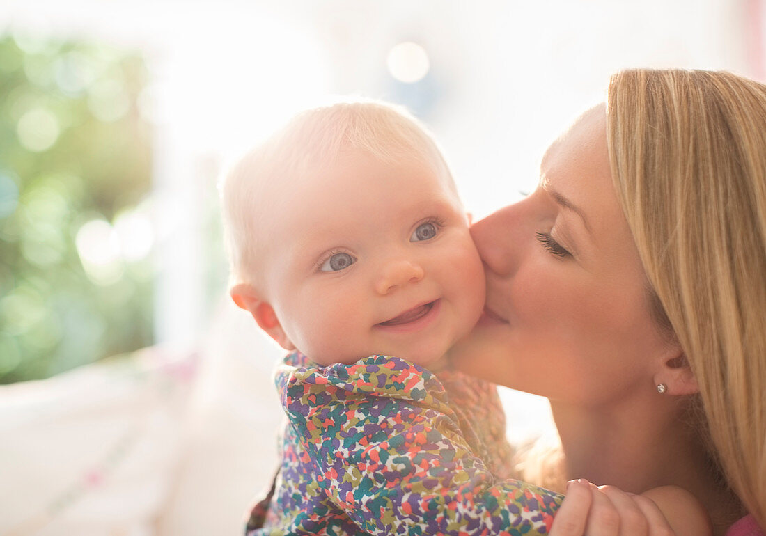 Mother kissing baby girl's cheek