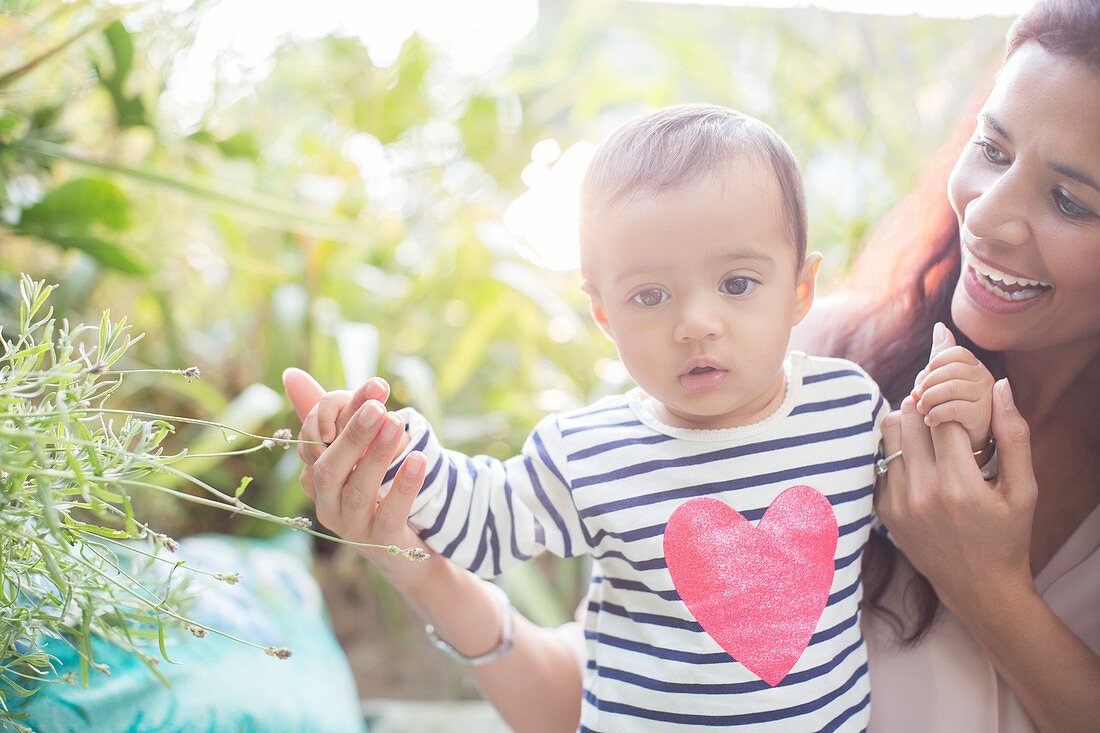 Mother helping baby boy walk outdoors