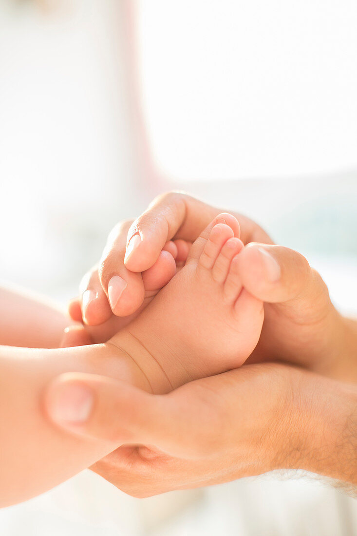 Father cradling baby boy's feet