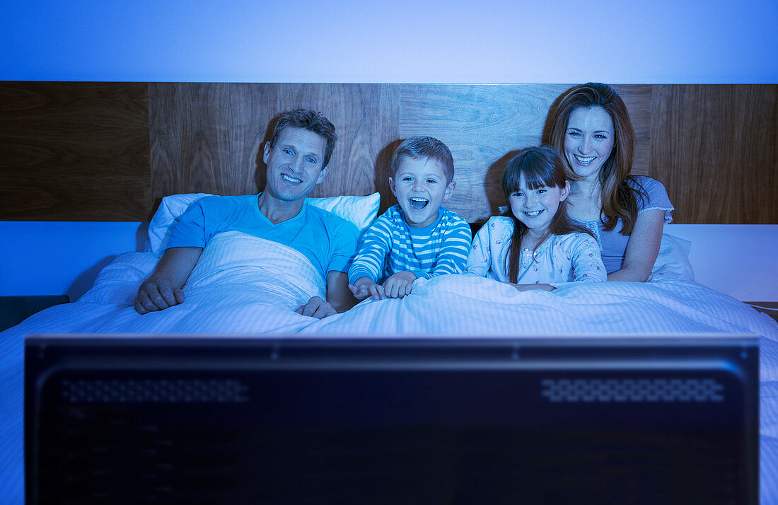 Family watching television in bed