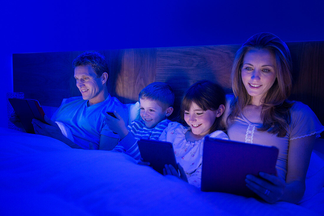 Family using technology in bed
