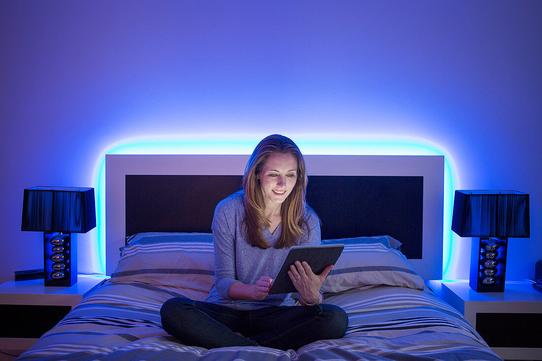 Woman using digital tablet on bed