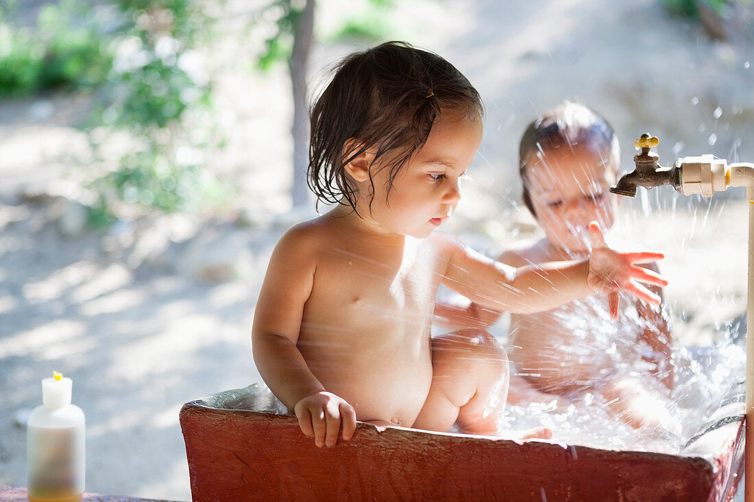 Baby girls playing in water spout