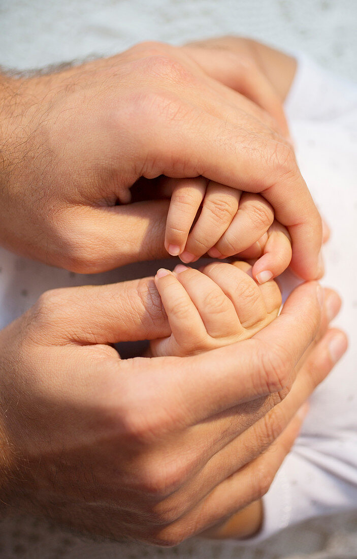 Father holding baby boy's hands