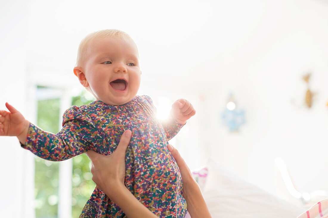 Mother holding baby girl in living room