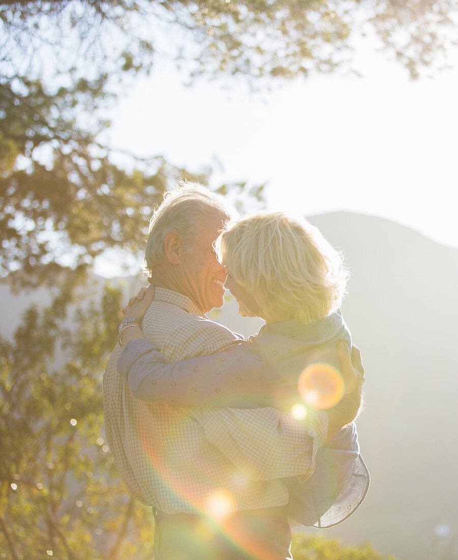 Senior man carrying woman outdoors