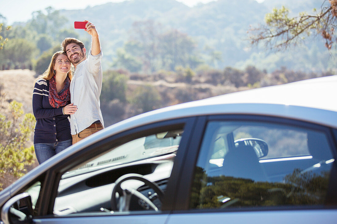 Couple taking self-portrait outside car