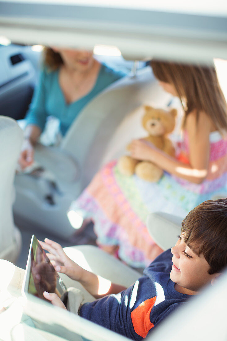 Boy using tablet in back seat of car