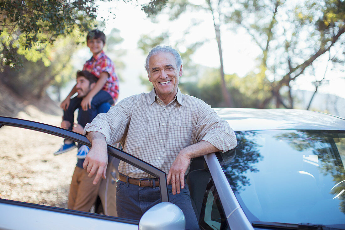 Portrait of senior man leaning on car