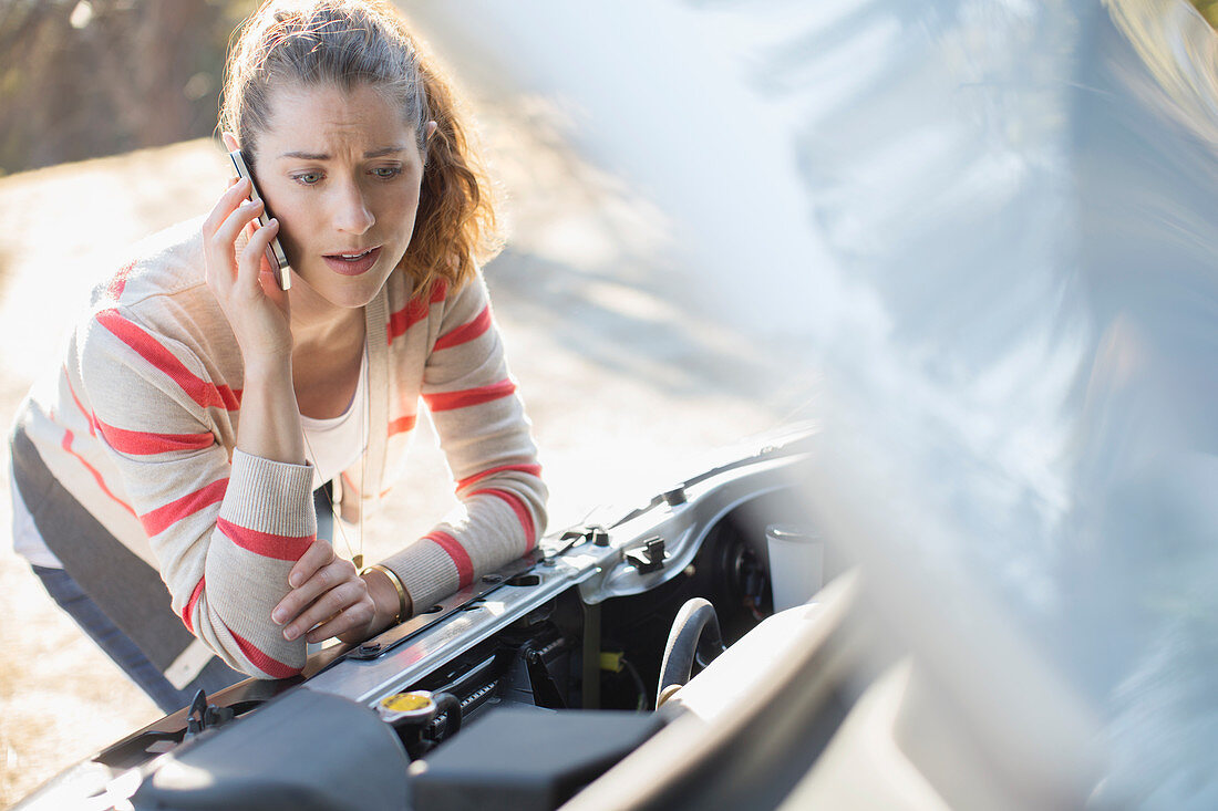 Frustrated woman looking at car engine