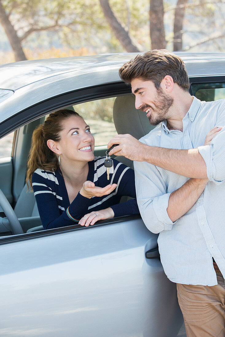 Man giving woman in car keys