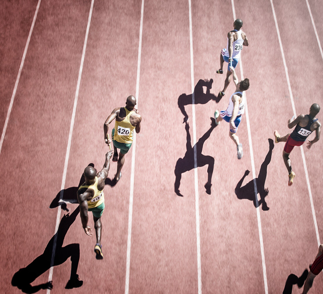 Relay runners handing off baton on track