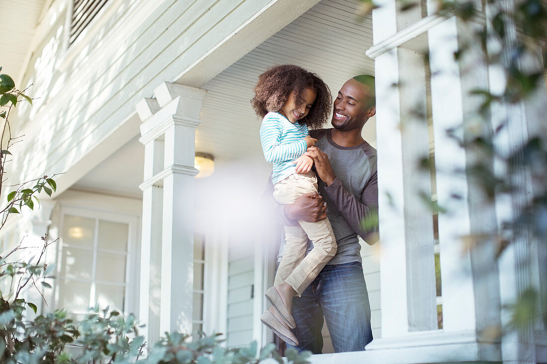 Happy father carrying daughter on porch