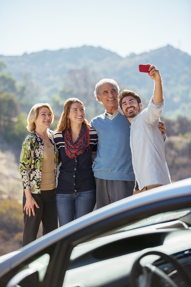 Family taking self-portrait outside car