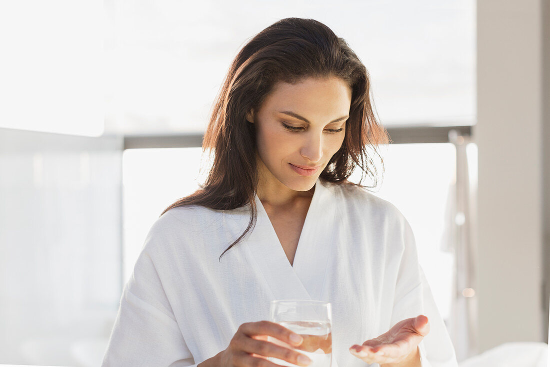 Woman in bathrobe taking medication