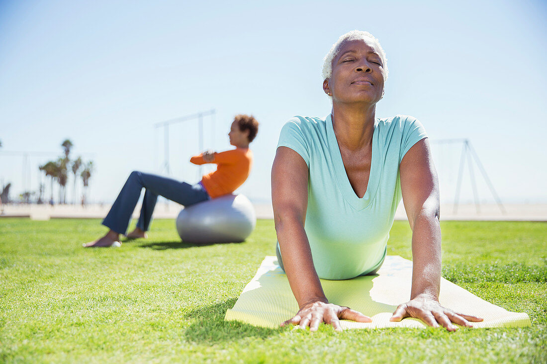 Women practicing yoga in sunny park