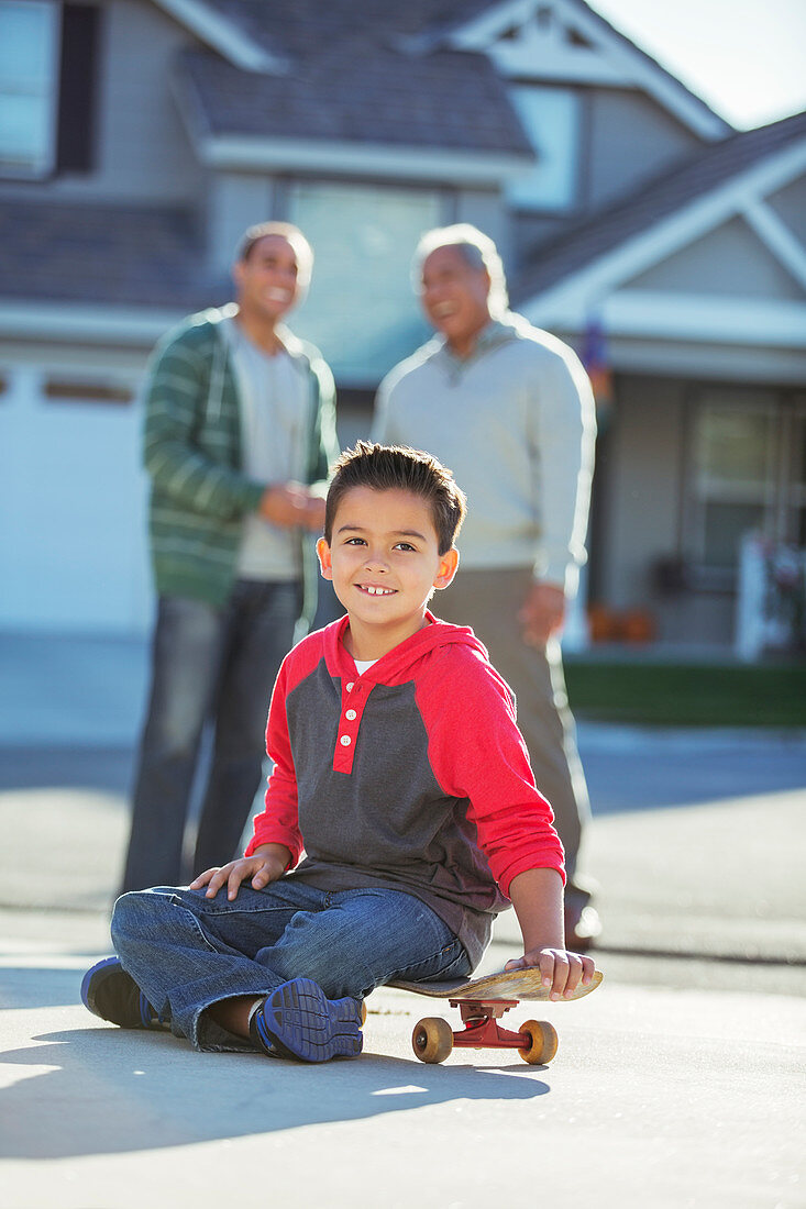 Smiling boy on skateboard in driveway