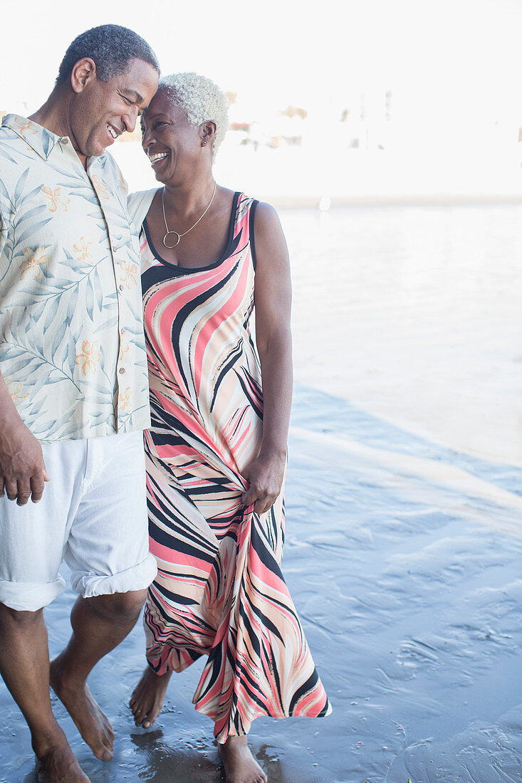 Senior couple walking barefoot on beach