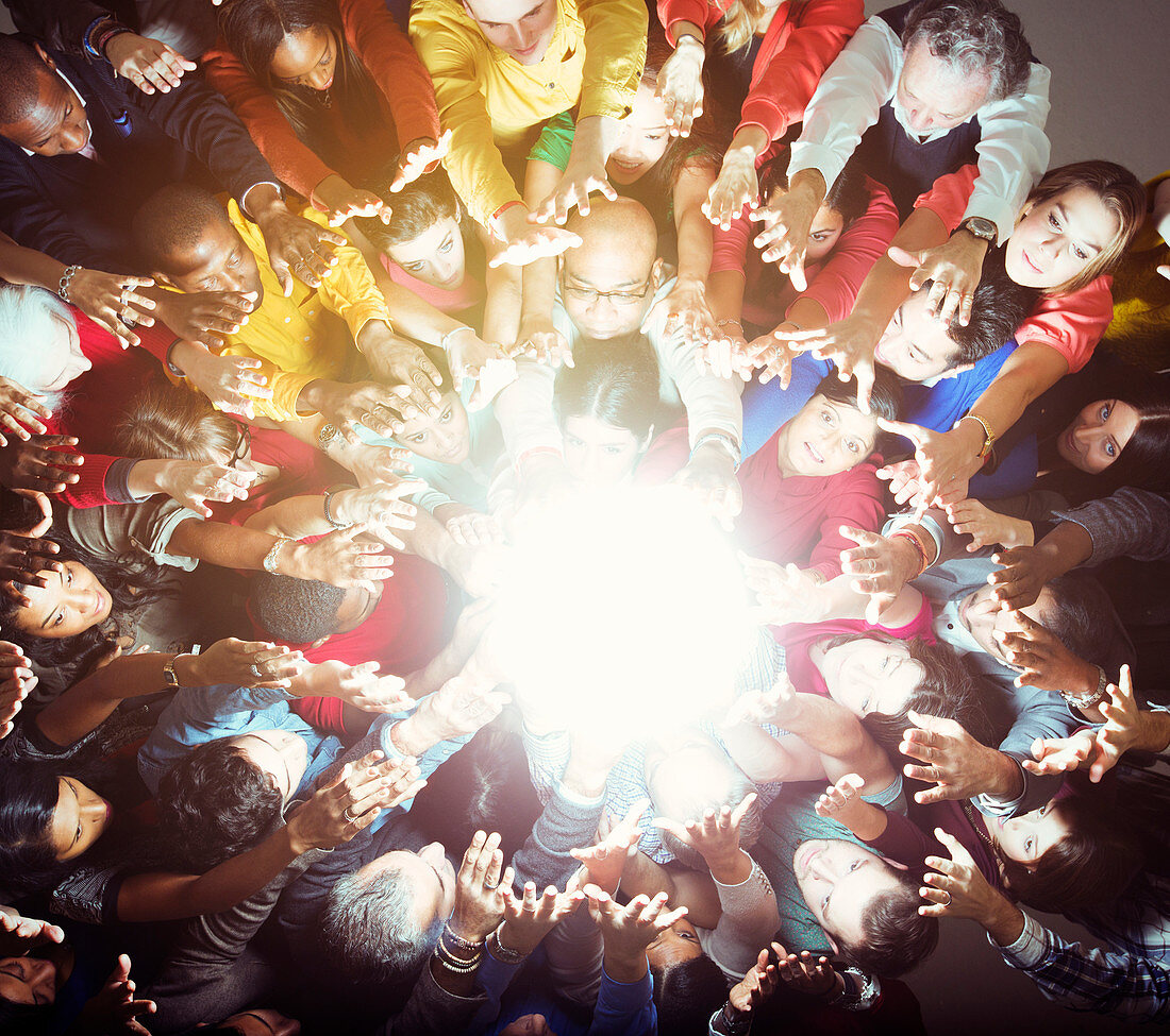 Diverse crowd reaching for bright light