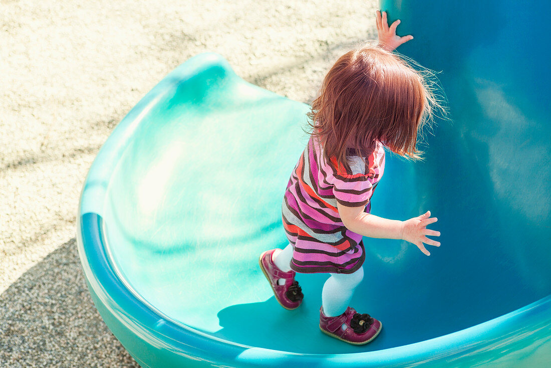 Baby girl climbing slide at playground