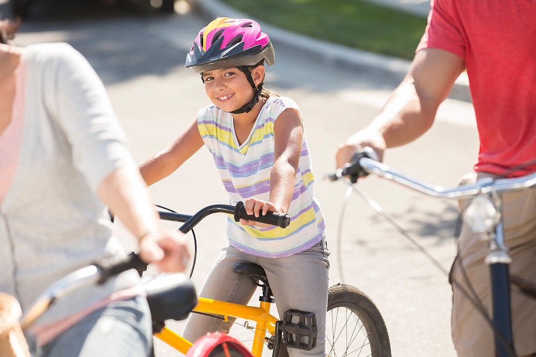 Smiling girl riding bicycle with parents
