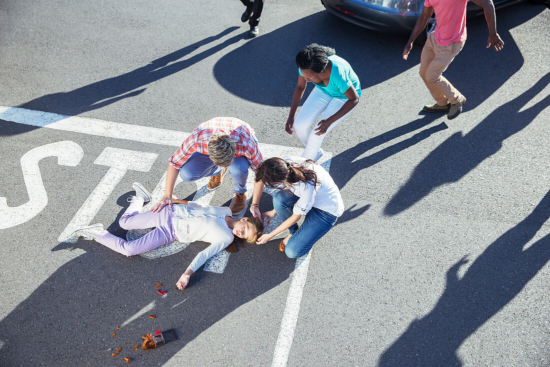 People examining injured girl on street