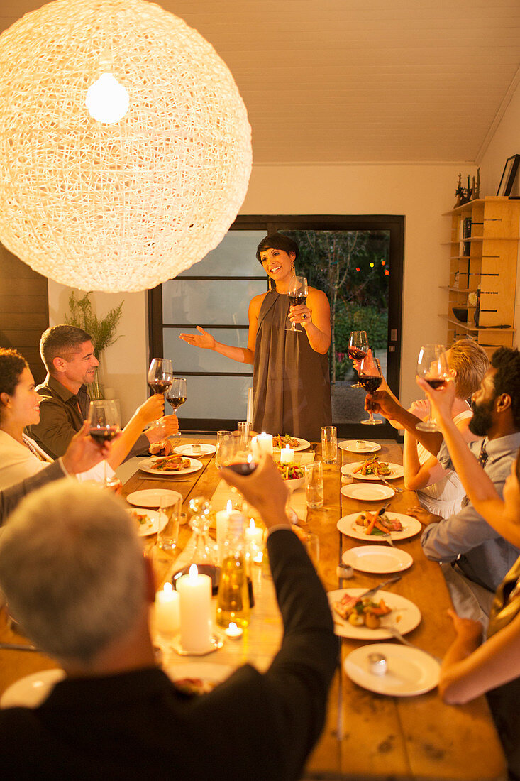 Woman giving toast at dinner party