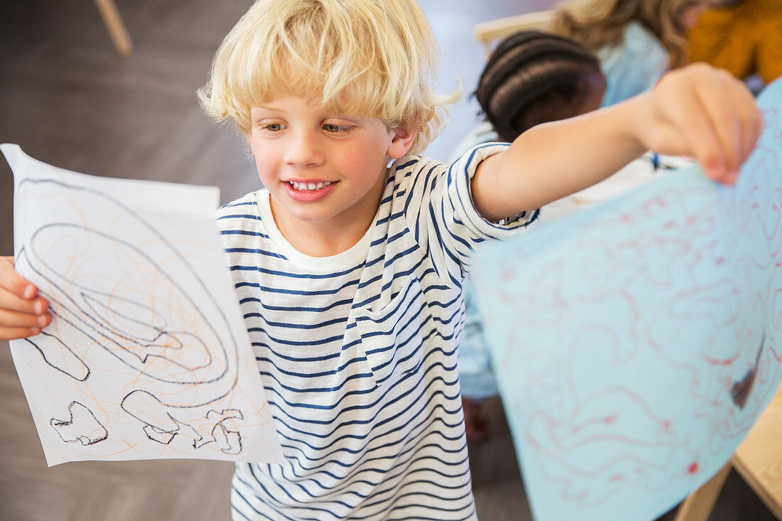 Student showing off drawings in classroom