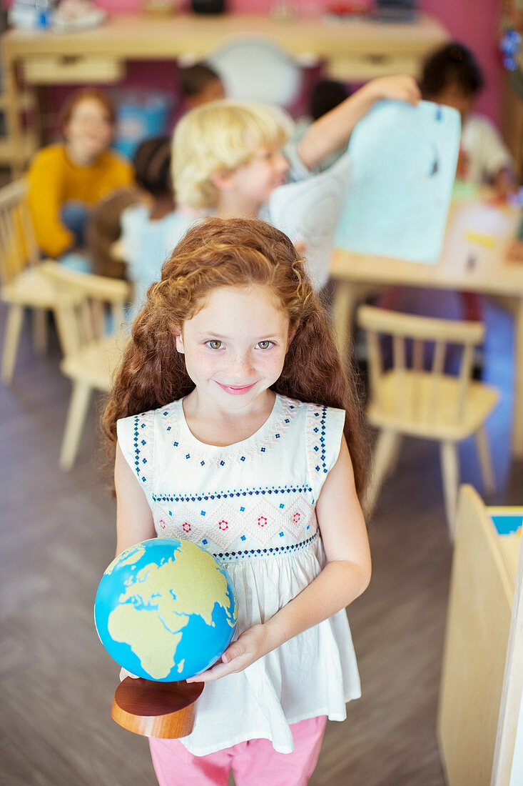Student holding globe in classroom